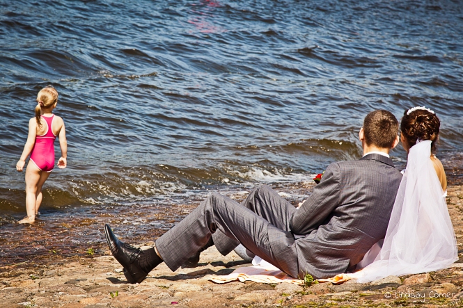 Newlyweds sitting by the river on Zayachiy Ostrov; Saint Petersburg, Russia.