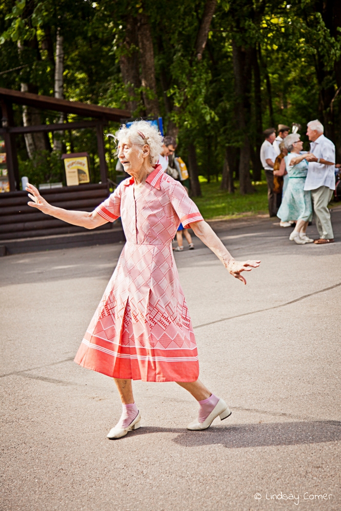 A babushka dancing on a summer afternoon in a park; Yelagin Ostrov, Saint Petersburg, Russia.